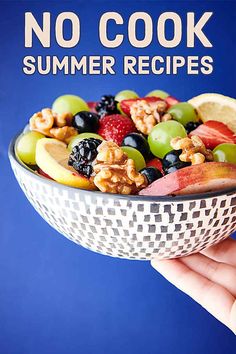 a hand holding a bowl filled with fruit and nuts