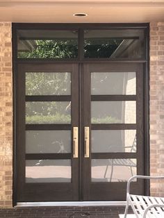 a white bench sitting in front of a building with two glass doors on each side