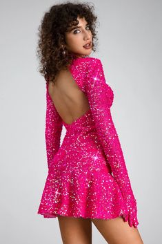 a woman in a bright pink dress with open back and sequins on it