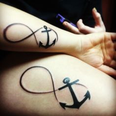 two people with tattoos on their arms and one has an anchor in the shape of a heart