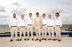 a group of men standing next to each other in front of a pool and ocean