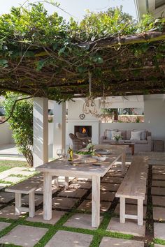 an outdoor dining area with wooden benches and greenery on the pergolated roof