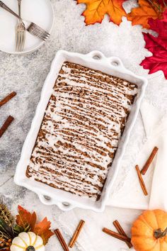 an image of a dessert in a pan with cinnamon sticks and pumpkins around it