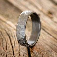 a wedding ring that is sitting on top of a wooden table with woodgrain