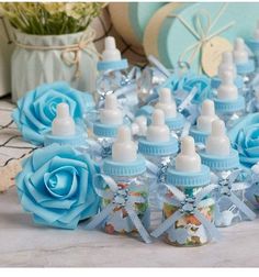 several baby blue bottles with white caps and bows are sitting on a table next to flowers