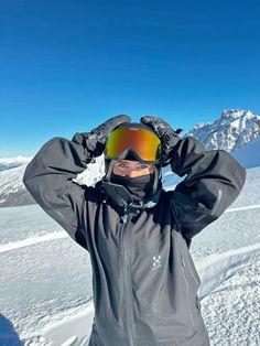 a man standing on top of a snow covered slope wearing skis and goggles