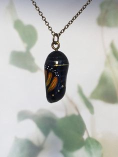 "The chrysalis - a symbol of transformation or metamorphosis. Gorgeous monarch butterfly chrysalis pendant, sculpted from clay and hand painted by me. This style is more contemporary than my realistic ones, more of an \"arty\" feel. No two are exactly the same. Comes with a 45cm (18 inch) chain in either gold tone, silver, antique bronze or black leather cord for a more bohemian feel. Please specify your choice when ordering :) Makes a beautiful gift for a girlfriend, wife or mother! Check my ot Unique Hand Painted Butterfly Jewelry, Unique Handmade Butterfly Necklace, Hand Painted Butterfly Jewelry Gift, Handmade Unique Butterfly Shaped Necklace, Handmade Unique Butterfly Necklace, Hand Painted Butterfly Jewelry For Gift, Monarch Chrysalis, Butterfly Chrysalis, Portfolio Ideas