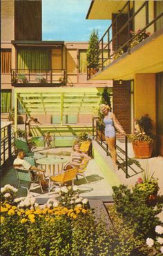 a woman in a bathing suit standing on the balcony of an apartment building with flowers and potted plants