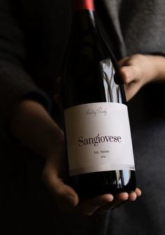 a person holding a bottle of wine in their hand with the label sanigovese on it