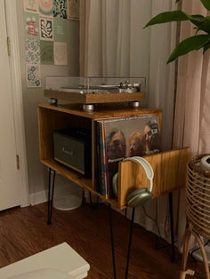 a record player sitting on top of a wooden shelf next to a plant in a living room