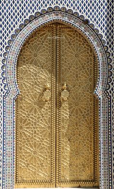 an intricately designed door with blue and white tiles on the side of a building