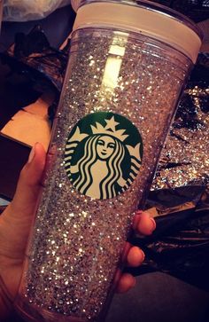 a person holding a starbucks cup with glitter on the bottom and one in their hand