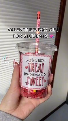 someone is holding up a cup with candy in it that says, valentine's day gift for students