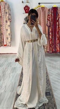 Discover our sumptuous Moroccan kaftan made from white Mobra fabric, an elegant choice that embodies both purity and refinement. The Mobra fabric, known for its soft and slightly satiny texture, offers a luxurious feel while maintaining a noble look. This kaftan, with a flowing and graceful cut, is enhanced by traditional silver thread embroidery that delicately runs along the collar, sleeves and hem, adding a touch of subtle sparkle. The embroidered patterns, inspired by Moroccan craftsmanship, bring an artistic dimension to this garment, while the immaculate white of the Mobra fabric highlights a timeless elegance. This caftan is ideal for ceremonies or special occasions where you want to combine tradition and modernity with distinction. The Mobra fabric, prized for its lightness and imp Caftan Dress Moroccan, Moroccan Wedding Dress, Embroidered Patterns, Moroccan Kaftan, Moroccan Wedding, Moroccan Caftan, Caftan Dress, Thread Embroidery, African Clothing