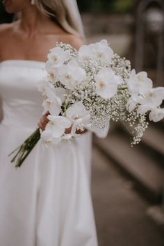 a bride holding a bouquet of white flowers