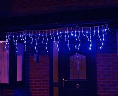 blue lights are hanging from the side of a brick building in front of a black door