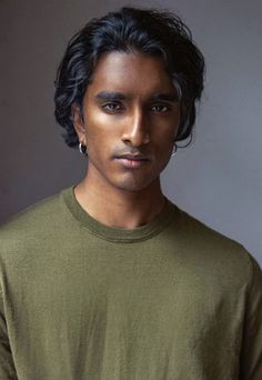 a man with black hair wearing a green shirt