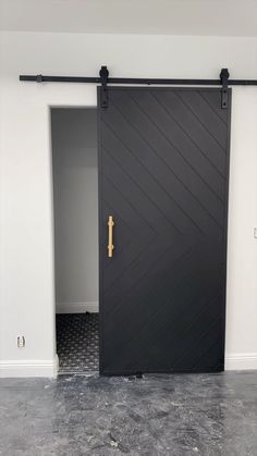 an open black door with a gold handle in the middle of a white walled room