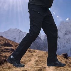 a man is walking up a hill with his foot in the air and wearing black shoes