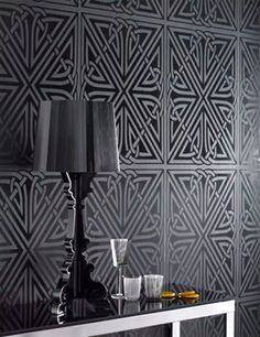 a black and white wallpaper with geometric designs on it's side table next to a lamp