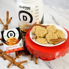 cookies and cinnamon sticks on a red plate next to a jar of d - motion