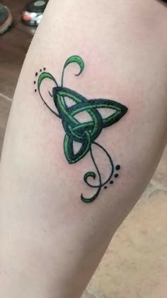 a green tattoo on the leg of a woman