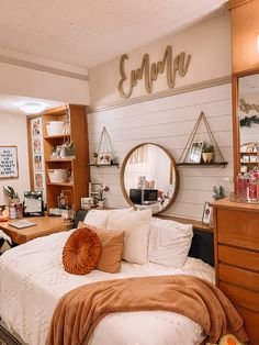 a bed room with a neatly made bed and a mirror on the wall above it