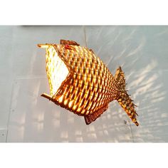 a fish shaped light hanging from the ceiling in front of a white wall with shadows on it