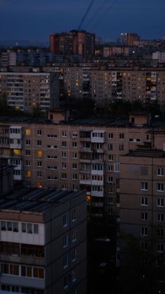 the city skyline is lit up at night with buildings in the foreground and power lines overhead