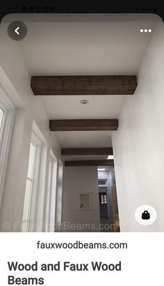 an empty hallway with white walls and wood beams on the ceiling is seen in this image