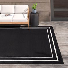 a black and white area rug sitting on top of a wooden floor next to a couch