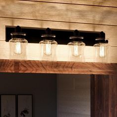 four mason jar lights are hanging from the ceiling above a vanity mirror in a bathroom