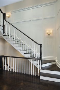 a white staircase with black handrails and wood flooring