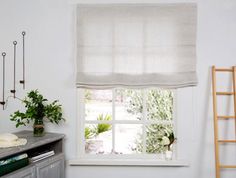 a white window in a room with a ladder and potted plant next to it