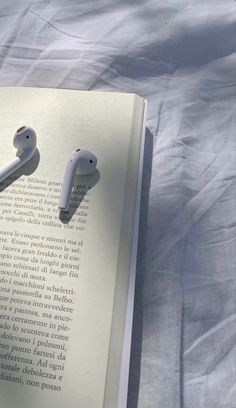 an open book with ear buds laying on it's side next to each other