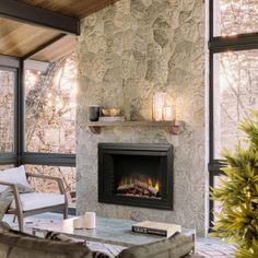 a living room filled with furniture and a fire place in front of a stone wall