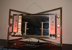 a mirror that is on top of a table with some lights around it and a light hanging from the ceiling