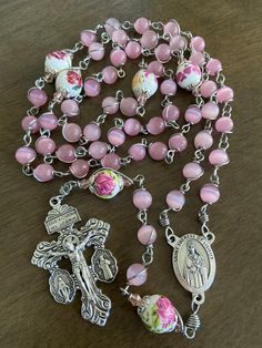 "This beautiful handmade rosary is made with 8mm cat's eye matte pink glass, 10mm ceramic beads and 2\" crucifix. Length: 27 inches long" Pink Rosary, Rosary Hand Made, Rosary Coquette, Handmade Pink Cross Rosary, Handmade Pink Rosary In Cross Shape, Handmade Pink Rosary With Cross, Handmade Pink Rosary With Cross Shape, Pink Rosary With 8mm Beads As Gift, Handmade Pink Rosary With Round Beads