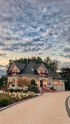 a large white house sitting on top of a lush green field under a cloudy sky