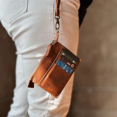 a person wearing white pants and holding a brown wallet