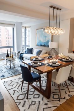 a dining room table and chairs in front of a large window with cityscape on the wall