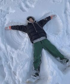 a person laying in the snow with their arms spread out and head on his back