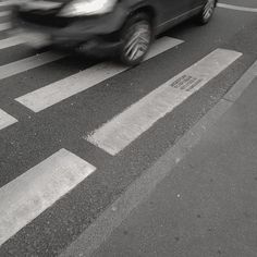 a car is driving down the street in black and white