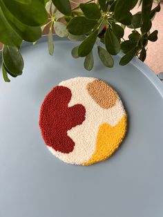 a round rug on top of a blue table next to a potted green plant