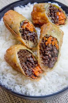 some food is sitting on top of rice in a black bowl and it looks like they are stuffed with meat