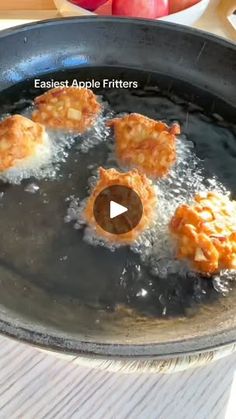 some food is being cooked in a frying pan on a table with an apple