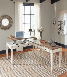 a desk with a laptop on it in front of a window and a plaid rug