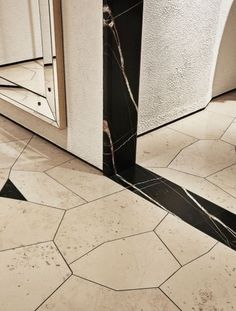 a bathroom with black and white marble flooring next to a mirror on the wall