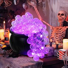 a table topped with lots of purple balloons next to candles and skeleton figurines