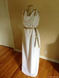 a white dress is on display in front of a wall and wood floored area